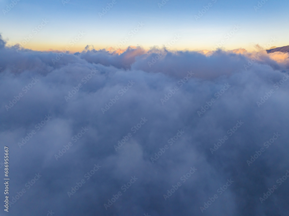 Aerial view of flowing fog waves on mountain tropical rainforest,Bird eye view image over the clouds Amazing nature background with clouds and mountain peaks in indonesia