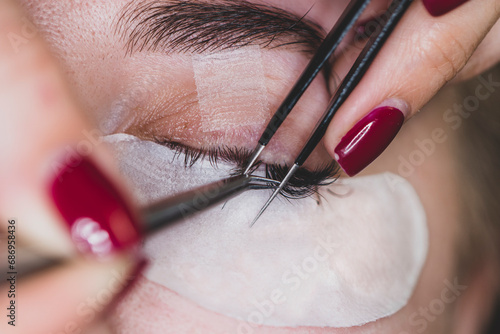 Woman Eye with Long Eyelashes. Eyelash Extension. Eyelash extension procedure - master and a client in beauty salon close-up.