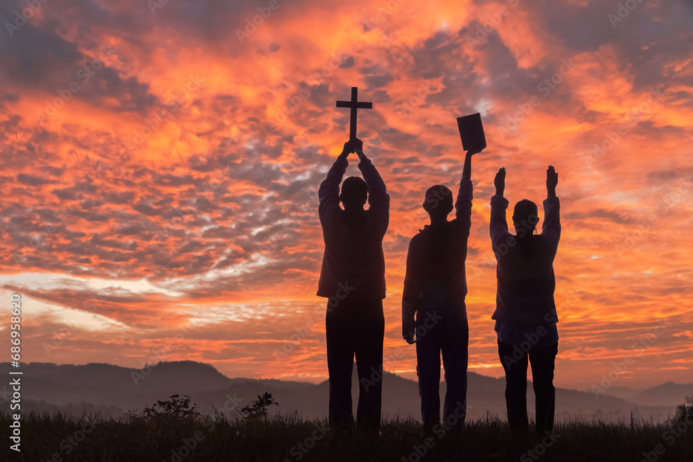 Φωτογραφία Silhouette people holding christian cross and bible for worshipping God on the mountain sunset sky background