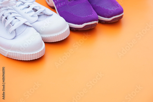 Head part of white and purple canvas sneakers. Orange background. Comfortable, fashionable. Concept, shoes for doing sport or exercise also can wear for traveling, hiking. 