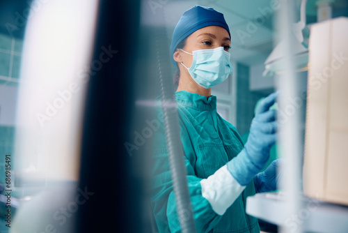 Female anesthesiologist checking monitor while sedating patient before surgery at clinic.