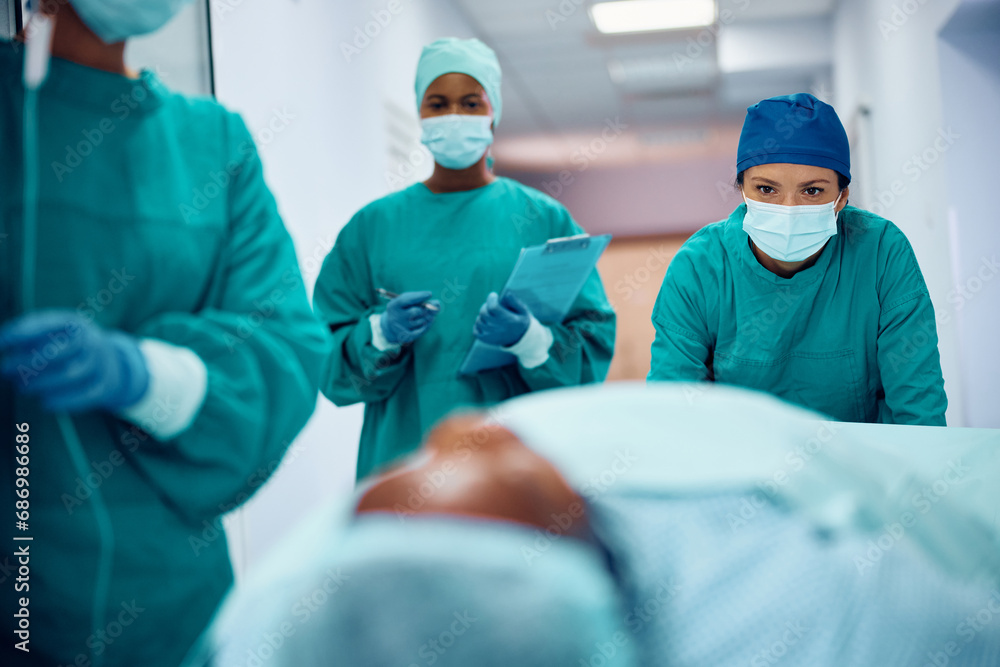 Female surgeon and her team taking patient to recovery room after surgery in hospital. Female surgeon and her team taking patient to recovery room after surgery in hospital.