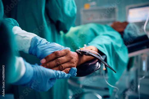 Close up of surgical nurse holding patient's hand in operating room.
