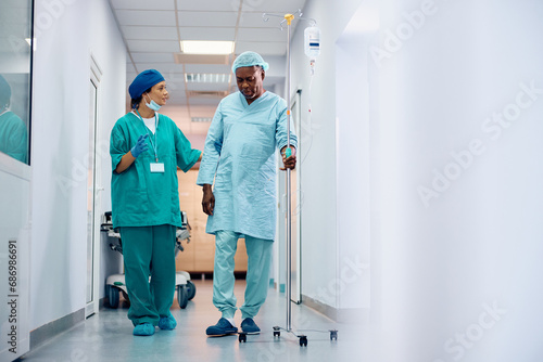 Female surgeon talks to senior black patient who is recovering after surgery.