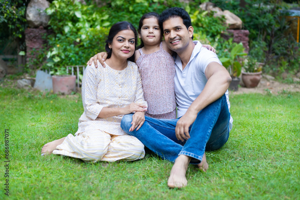 Happy indian family sitting in the park or garden. Young parent with cute little daughter. Happy indian family sitting in the park or garden. Young parent with cute little daughter.