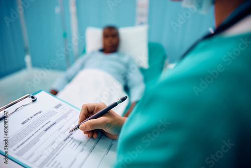 Close up of female doctor writes in medical data while visiting her patient in hospital ward. photo