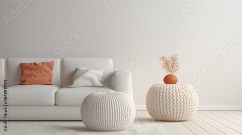 Knitted pouf near white fabric sofa with blanket and terra cotta pillows. Scandinavian, hygge style home interior design of modern living room photo