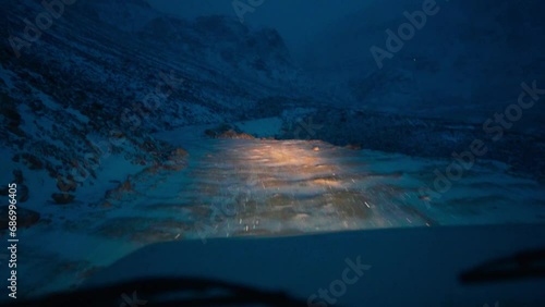 POV shot of vehicle driving on snowy road in Himalayas during snowfall at Manali, India. Slippery road during winters. Risky road in the mountains. Snowfall during night. photo