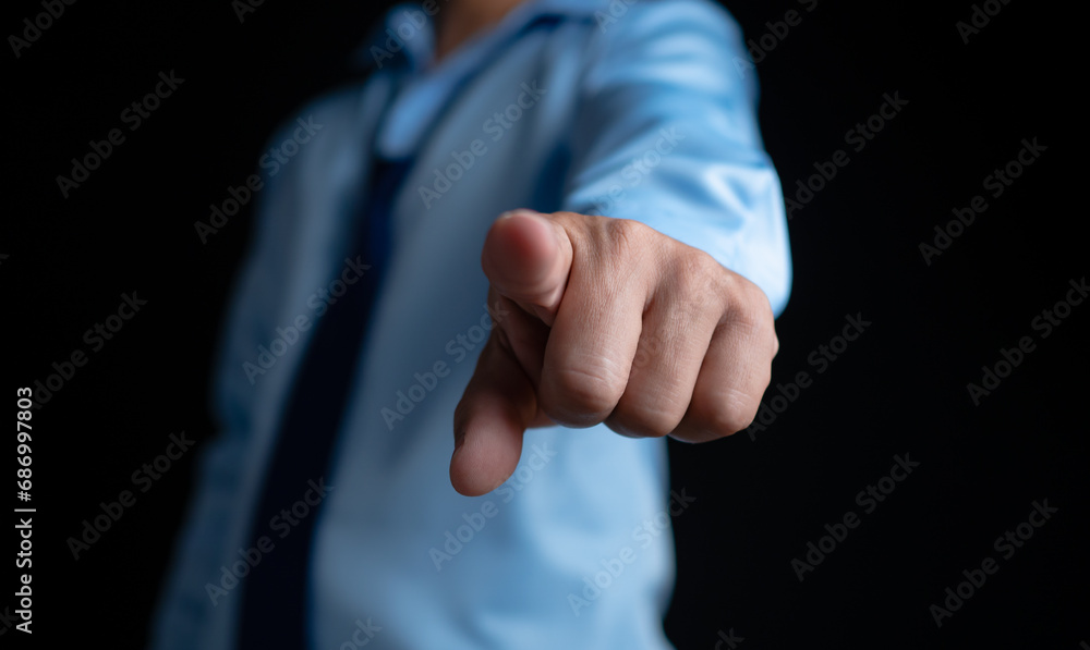 Employee makes a forward pointing gesture on a dark background. Employee makes a forward pointing gesture on a dark background.