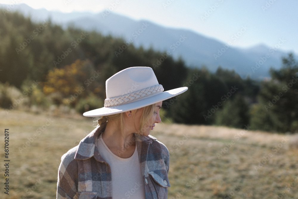 Portrait of a beautiful girl in a fashionable hat near the mountains.