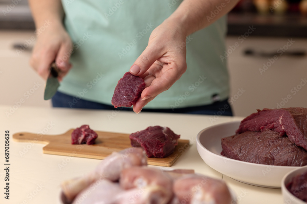 A woman's hand with a piece of beef in close-up. Cooking dinner