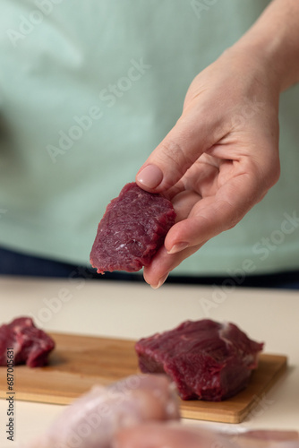 A woman's hand with a piece of beef in close-up.