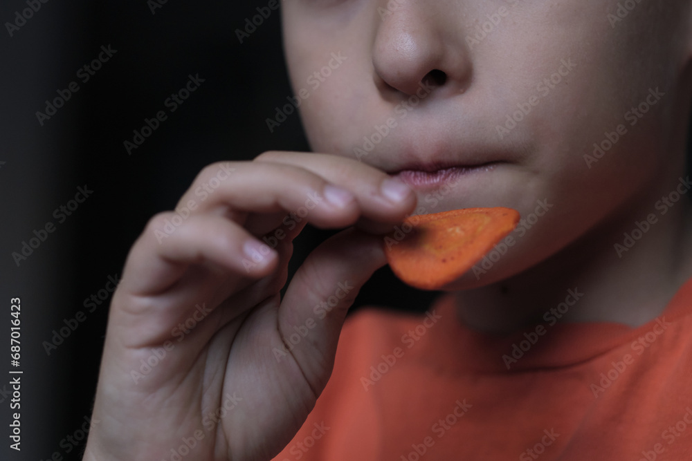 Close-up of a child's hand holding a spicy chip, capturing a quiet moment of simple indulgence and the small joys of childhood snacks. Close-up of a child's hand holding a spicy chip, capturing a quiet moment of simple indulgence and the small joys of childhood snacks.