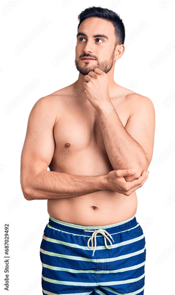 Fototapeta premium Young handsome man wearing swimwear with hand on chin thinking about question, pensive expression. smiling and thoughtful face. doubt concept.