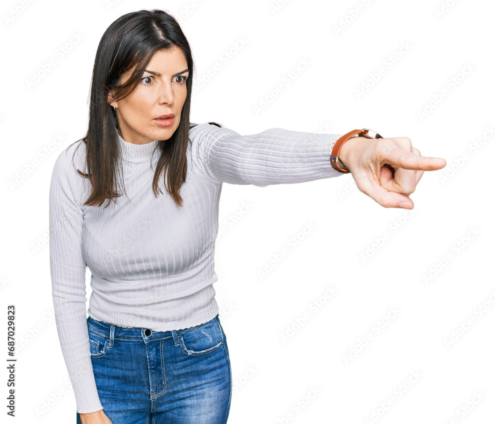 Beautiful brunette woman wearing casual clothes pointing with finger surprised ahead, open mouth amazed expression, something on the front Beautiful brunette woman wearing casual clothes pointing with finger surprised ahead, open mouth amazed expression, something on the front