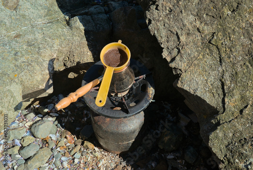 Gas burner with a Turk for making coffee in the field among rocks in nature