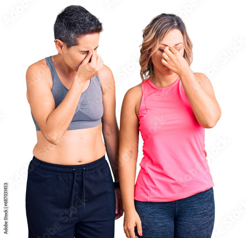 Couple of women wearing sportswear tired rubbing nose and eyes feeling fatigue and headache. stress and frustration concept.