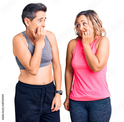 Couple of women wearing sportswear looking stressed and nervous with hands on mouth biting nails. anxiety problem.