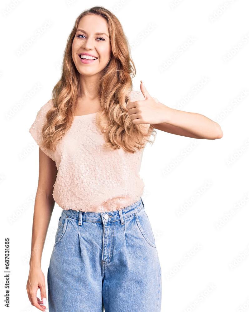 Young beautiful caucasian woman with blond hair wearing casual clothes doing happy thumbs up gesture with hand. approving expression looking at the camera showing success. Young beautiful caucasian woman with blond hair wearing casual clothes doing happy thumbs up gesture with hand. approving expression looking at the camera showing success.