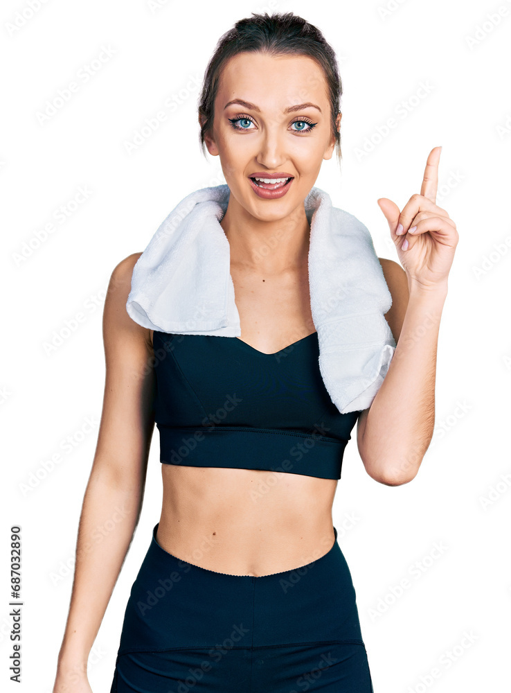 Beautiful caucasian woman wearing sportswear and towel pointing finger up with successful idea. exited and happy. number one. Beautiful caucasian woman wearing sportswear and towel pointing finger up with successful idea. exited and happy. number one.