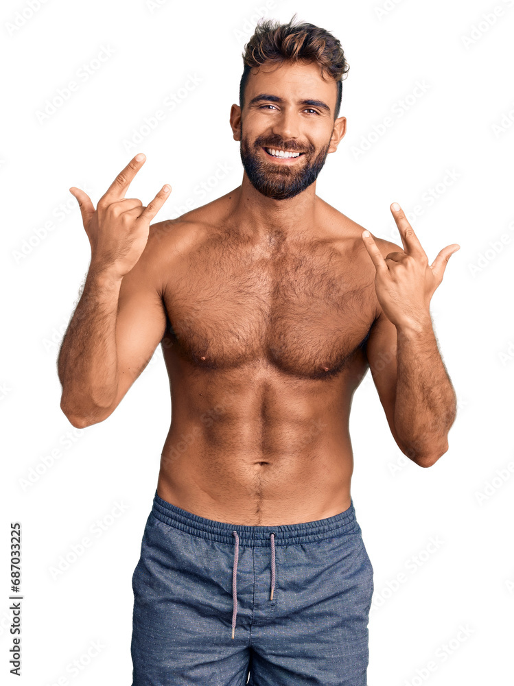 Young hispanic man wearing swimwear shirtless shouting with crazy expression doing rock symbol with hands up. music star. heavy concept. Young hispanic man wearing swimwear shirtless shouting with crazy expression doing rock symbol with hands up. music star. heavy concept.