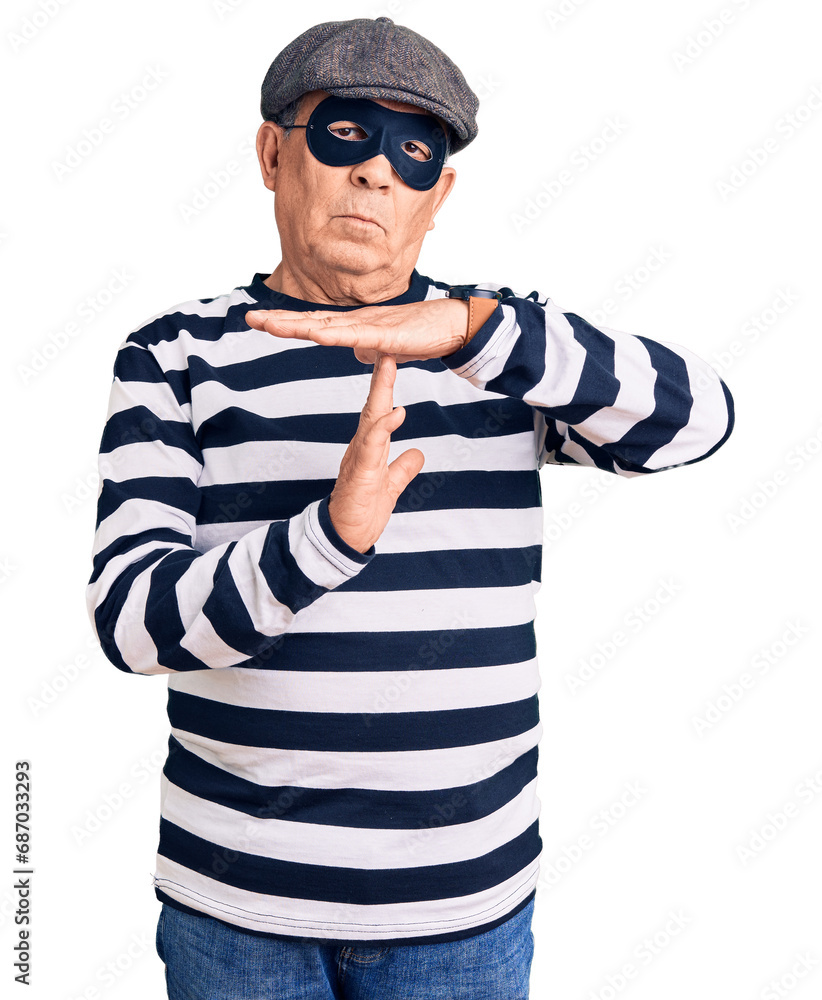 Senior handsome man wearing burglar mask and t-shirt doing time out gesture with hands, frustrated and serious face Senior handsome man wearing burglar mask and t-shirt doing time out gesture with hands, frustrated and serious face