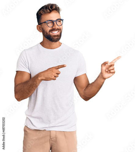 Young hispanic man wearing casual clothes and glasses smiling and looking at the camera pointing with two hands and fingers to the side.