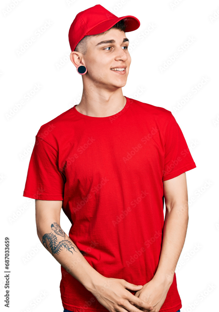 Fototapeta premium Young caucasian boy with ears dilation wearing delivery uniform and cap looking away to side with smile on face, natural expression. laughing confident.