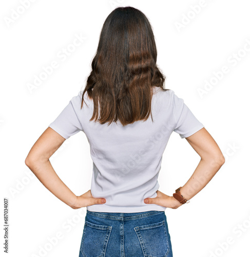 Young beautiful woman wearing casual white t shirt standing backwards looking away with arms on body photo