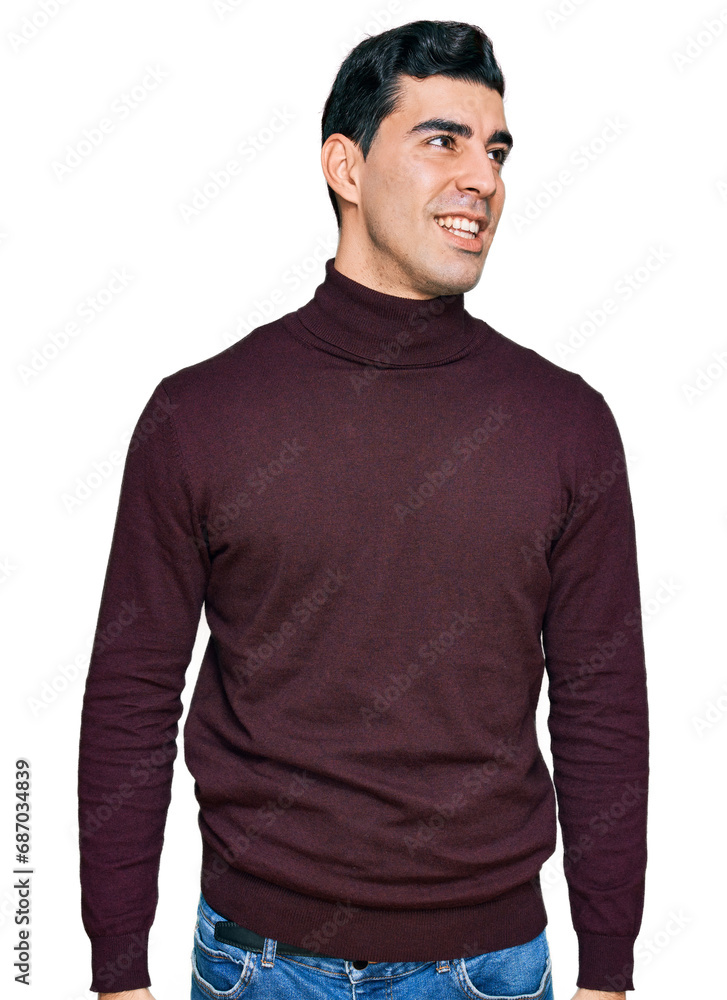 Fototapeta premium Handsome hispanic man wearing casual turtleneck sweater looking away to side with smile on face, natural expression. laughing confident.