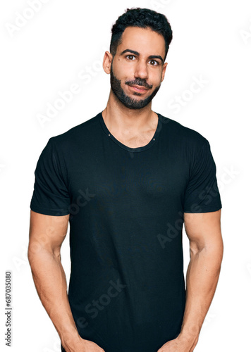 Hispanic man with beard wearing casual black t shirt puffing cheeks with funny face. mouth inflated with air, crazy expression.