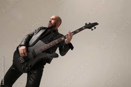 Rock musician. A man with shaved head poses at the studio in black clothes. 