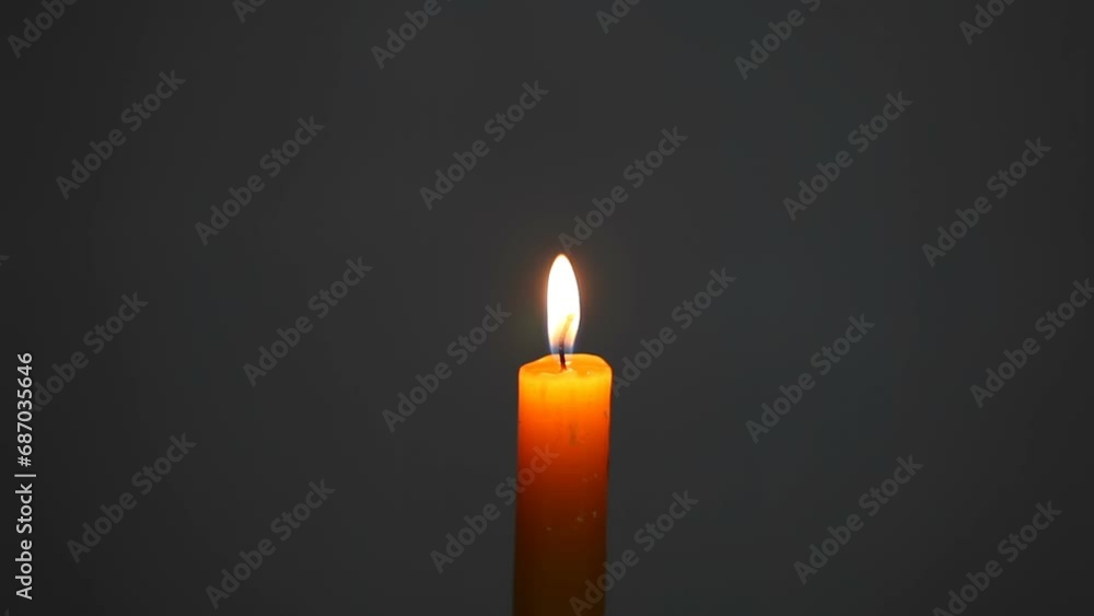 A man extinguishes a burning wax candle with his fingers. A candle burns on a gray background. Free space for text. A man extinguishes a burning wax candle with his fingers. A candle burns on a gray background. Free space for text.