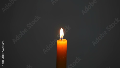 A man extinguishes a burning wax candle with his fingers. A candle burns on a gray background. Free space for text.