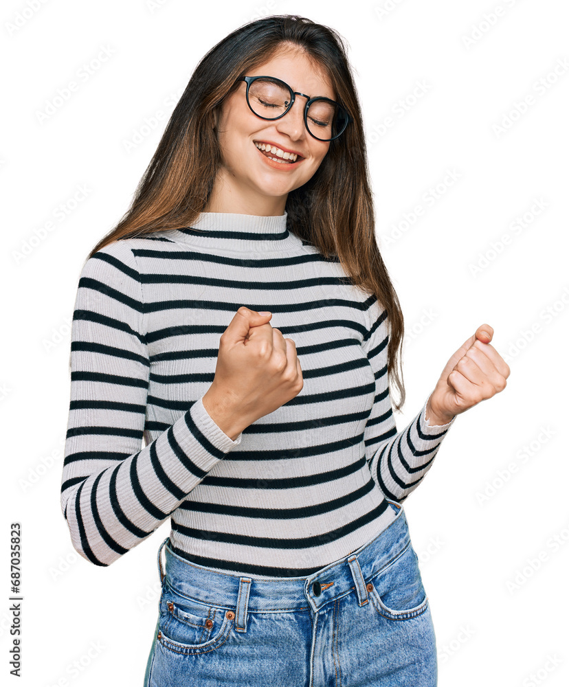 Young beautiful teen girl wearing casual clothes and glasses excited for success with arms raised and eyes closed celebrating victory smiling. winner concept. Young beautiful teen girl wearing casual clothes and glasses excited for success with arms raised and eyes closed celebrating victory smiling. winner concept.