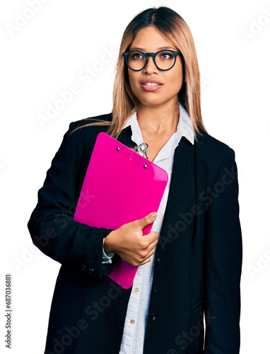 Young hispanic business woman holding clipboard with blank space looking sleepy and tired, exhausted for fatigue and hangover, lazy eyes in the morning.