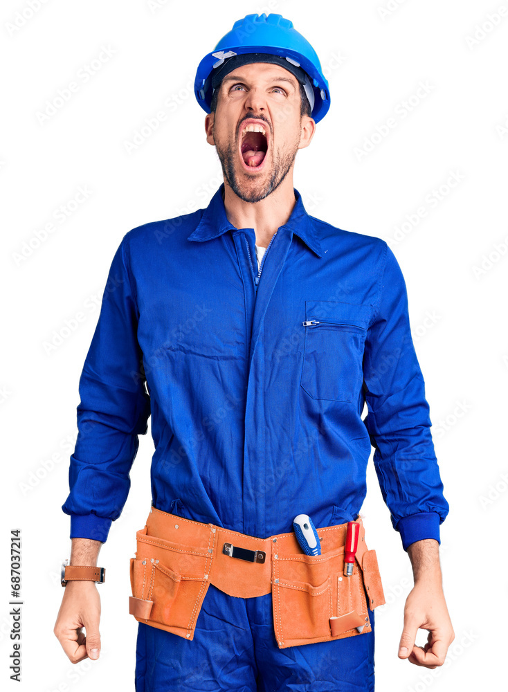 Young handsome man wearing worker uniform and hardhat angry and mad raising fists frustrated and furious while shouting with anger. rage and aggressive concept. Young handsome man wearing worker uniform and hardhat angry and mad raising fists frustrated and furious while shouting with anger. rage and aggressive concept.