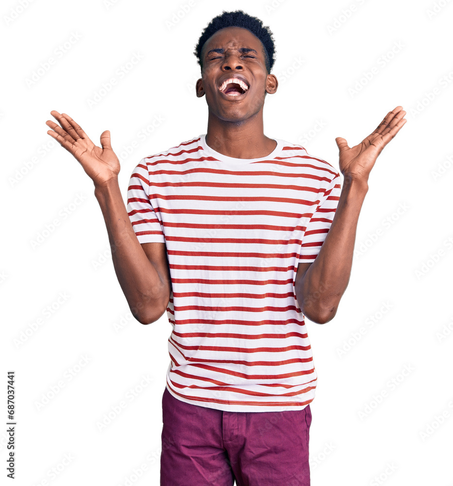 Young african american man wearing casual clothes celebrating mad and crazy for success with arms raised and closed eyes screaming excited. winner concept Young african american man wearing casual clothes celebrating mad and crazy for success with arms raised and closed eyes screaming excited. winner concept