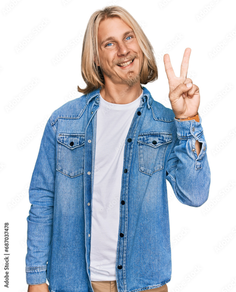 Caucasian man with blond long hair wearing casual denim jacket showing and pointing up with fingers number two while smiling confident and happy. Caucasian man with blond long hair wearing casual denim jacket showing and pointing up with fingers number two while smiling confident and happy.