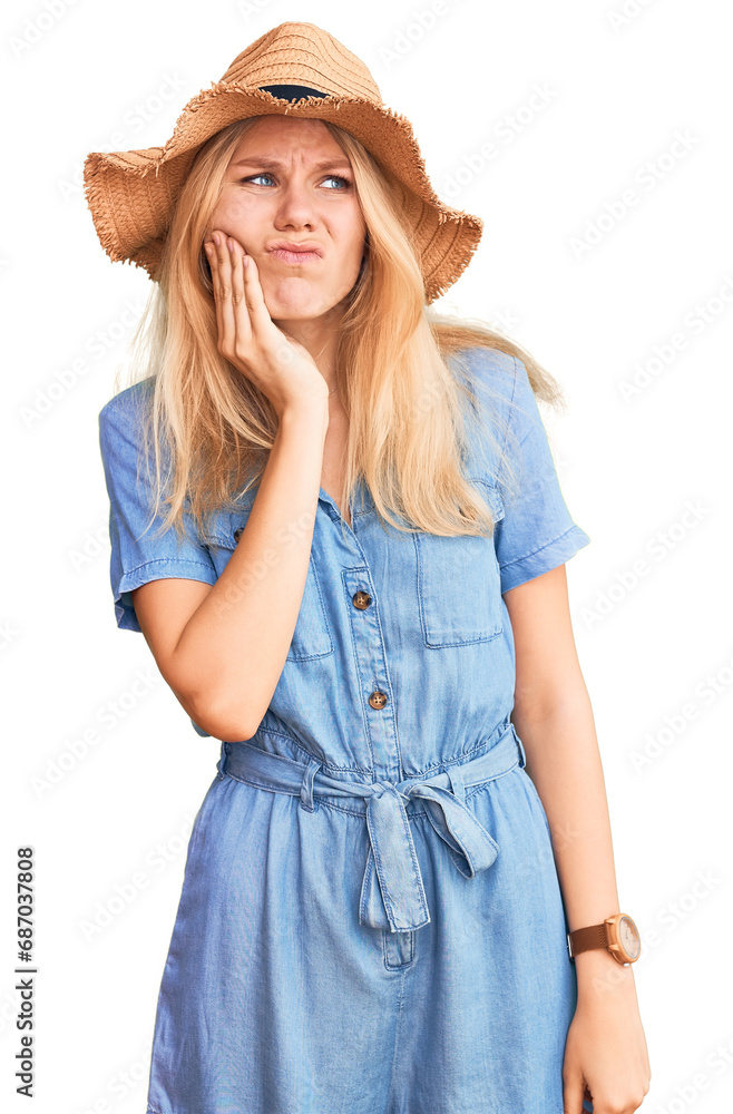 Young beautiful blonde woman wearing summer hat and dress touching mouth with hand with painful expression because of toothache or dental illness on teeth. dentist Young beautiful blonde woman wearing summer hat and dress touching mouth with hand with painful expression because of toothache or dental illness on teeth. dentist