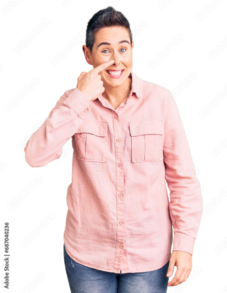 Young woman with short hair wearing casual clothes pointing with hand finger to face and nose, smiling cheerful. beauty concept Young woman with short hair wearing casual clothes pointing with hand finger to face and nose, smiling cheerful. beauty concept