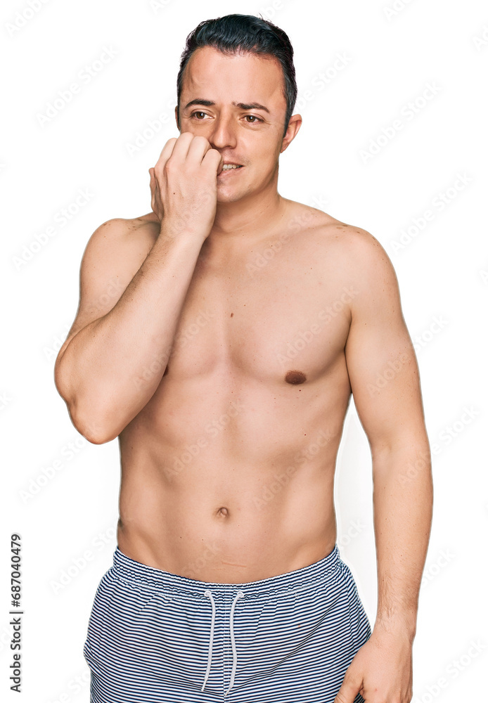 Fototapeta premium Handsome young man wearing swimwear shirtless looking stressed and nervous with hands on mouth biting nails. anxiety problem.