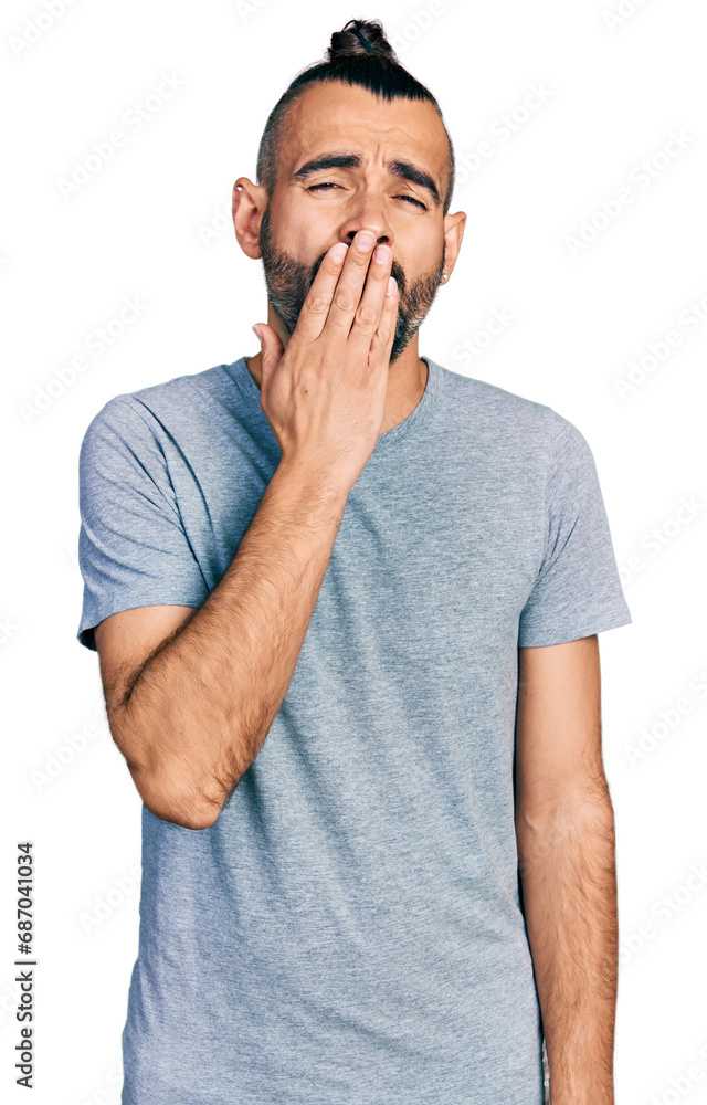 Hispanic man with ponytail wearing casual grey t shirt bored yawning tired covering mouth with hand. restless and sleepiness. Hispanic man with ponytail wearing casual grey t shirt bored yawning tired covering mouth with hand. restless and sleepiness.