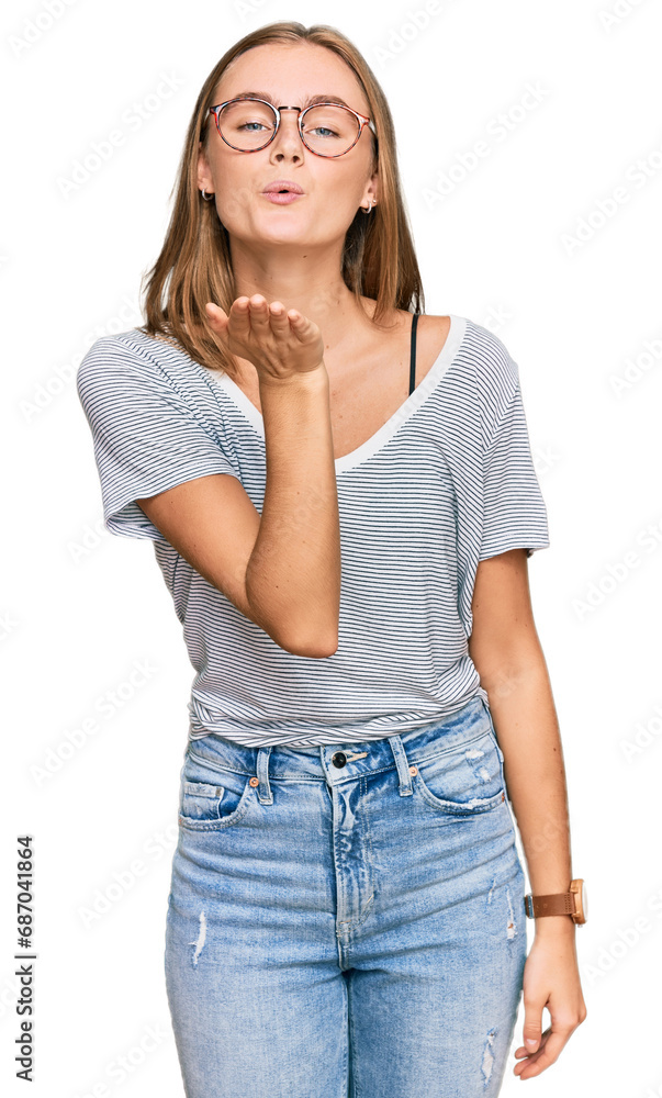 Beautiful young blonde woman wearing casual clothes and glasses looking at the camera blowing a kiss with hand on air being lovely and sexy. love expression. Beautiful young blonde woman wearing casual clothes and glasses looking at the camera blowing a kiss with hand on air being lovely and sexy. love expression.