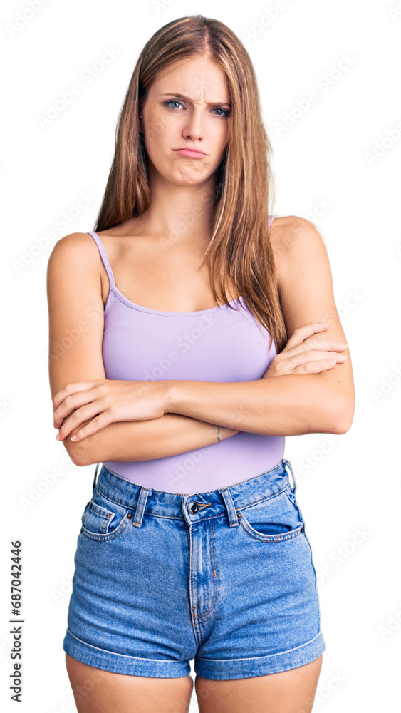 Young beautiful blonde woman wearing casual style with sleeveless shirt skeptic and nervous, disapproving expression on face with crossed arms. negative person. Young beautiful blonde woman wearing casual style with sleeveless shirt skeptic and nervous, disapproving expression on face with crossed arms. negative person.