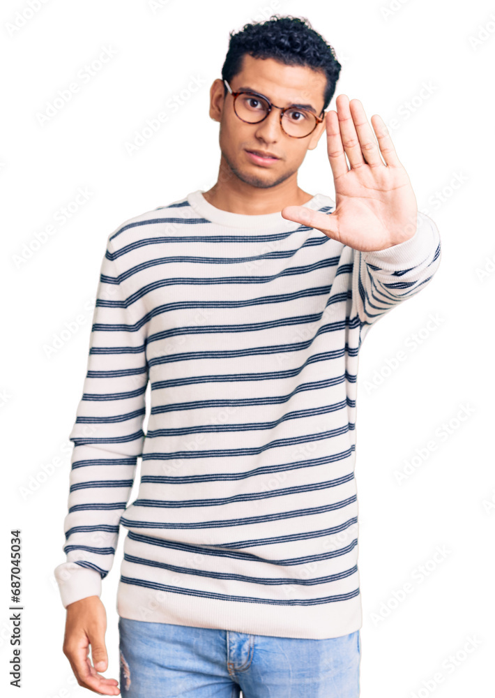 Hispanic handsome young man wearing casual clothes and glasses doing stop sing with palm of the hand. warning expression with negative and serious gesture on the face. Hispanic handsome young man wearing casual clothes and glasses doing stop sing with palm of the hand. warning expression with negative and serious gesture on the face.