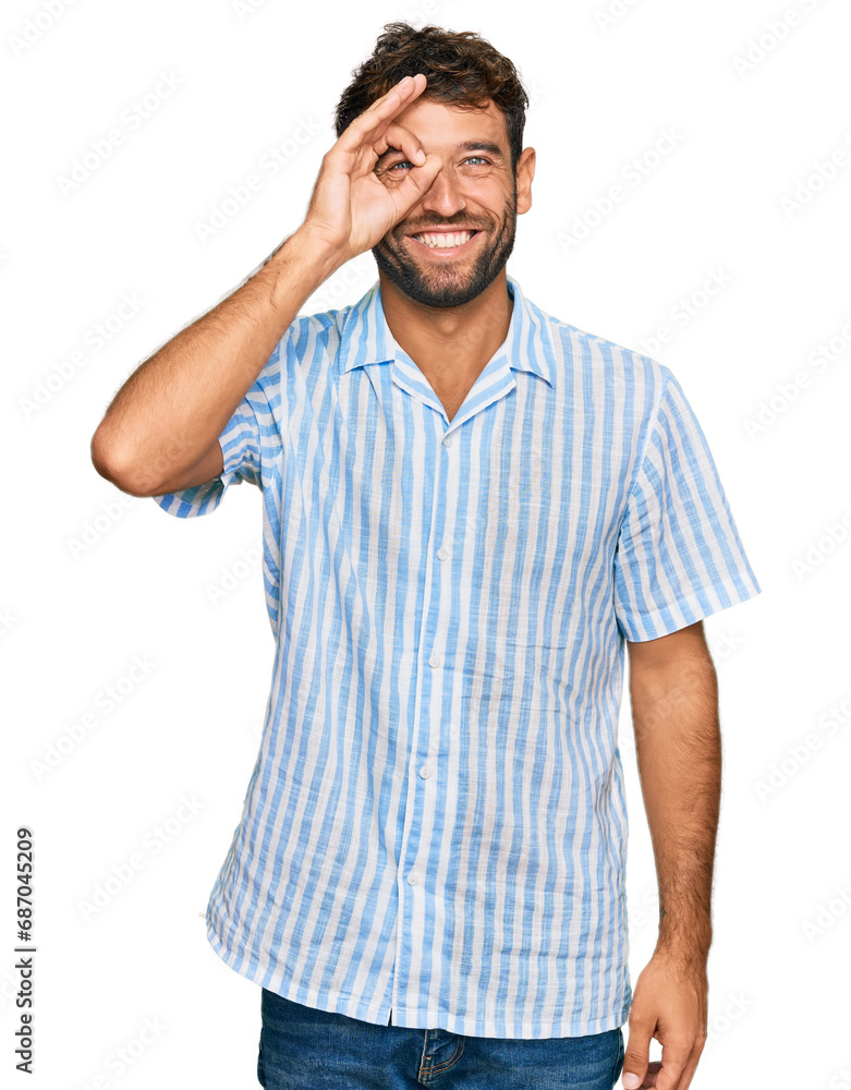 Handsome young man with beard wearing casual fresh shirt doing ok gesture with hand smiling, eye looking through fingers with happy face. Handsome young man with beard wearing casual fresh shirt doing ok gesture with hand smiling, eye looking through fingers with happy face.