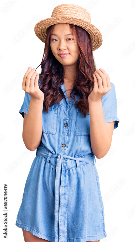Young beautiful chinese girl wearing summer hat doing money gesture with hands, asking for salary payment, millionaire business Young beautiful chinese girl wearing summer hat doing money gesture with hands, asking for salary payment, millionaire business