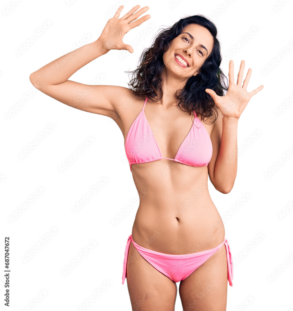 Young beautiful hispanic woman wearing bikini showing and pointing up with fingers number ten while smiling confident and happy. Young beautiful hispanic woman wearing bikini showing and pointing up with fingers number ten while smiling confident and happy.