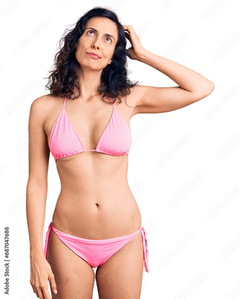 Fototapeta premium Young beautiful hispanic woman wearing bikini confuse and wondering about question. uncertain with doubt, thinking with hand on head. pensive concept.